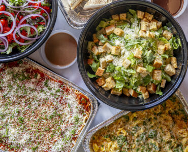 Overhead shot of salads, entrees, and desserts arranged in catering dishes on a table