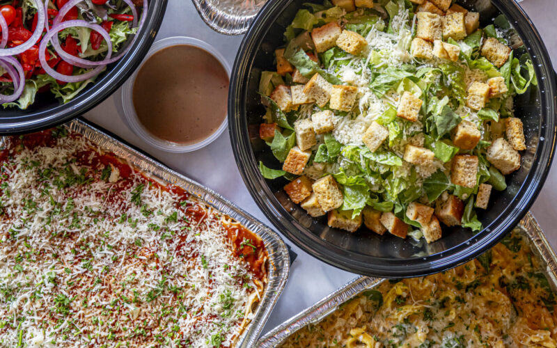 Overhead shot of salads, entrees, and desserts arranged in catering dishes on a table